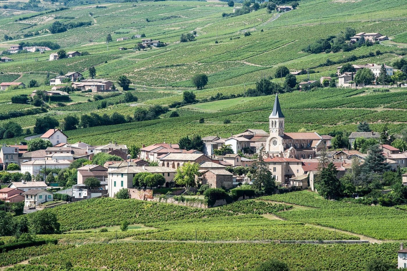 Vila de Juliénas com sua igreja cercada por vinhedos ondulados no Beaujolais