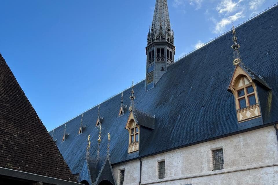 Hospices de Beaune com telhado de ardósia e flecha sob céu azul
