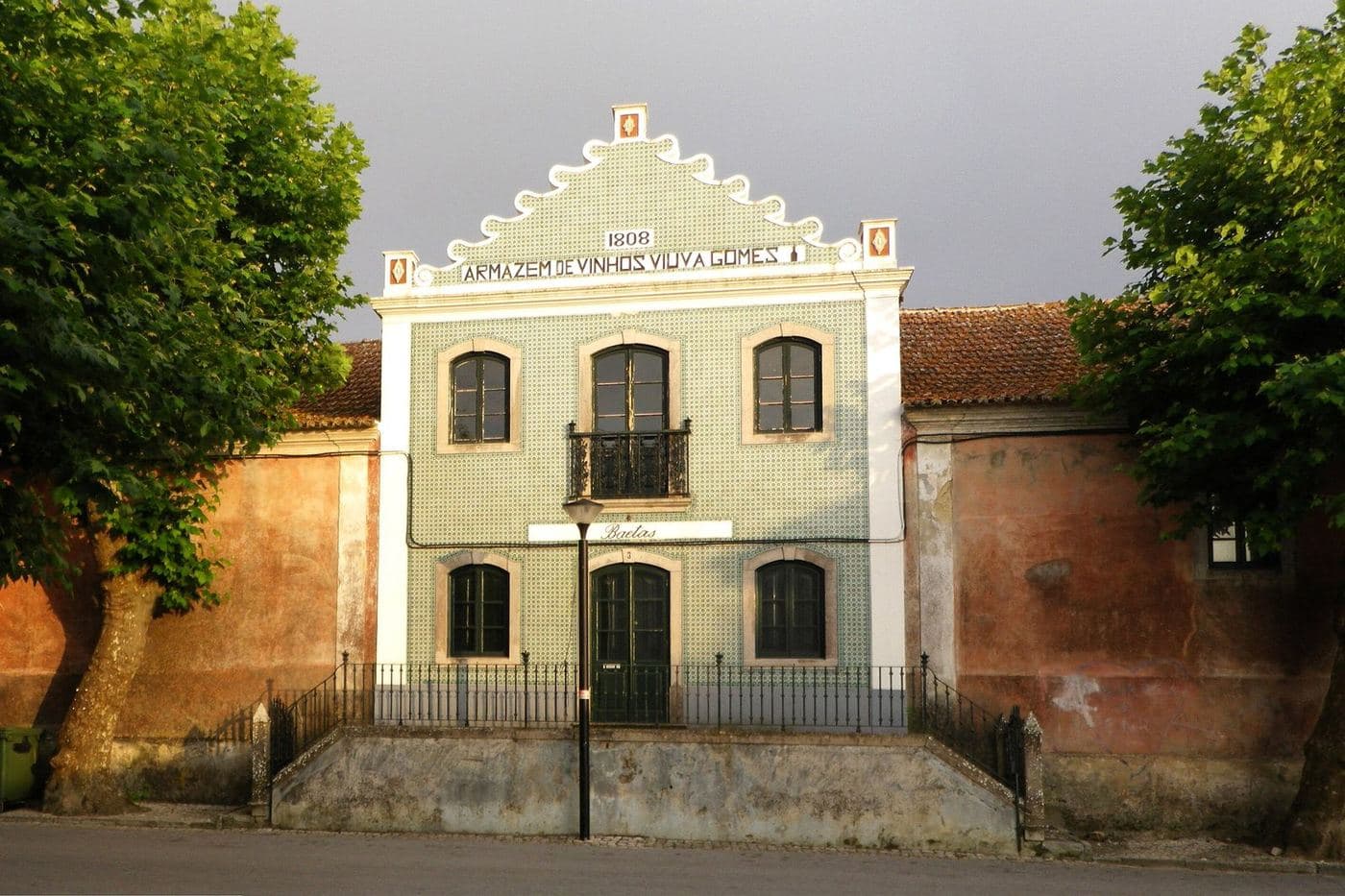 Fachada azulejada do histórico armazém de vinhos de Colares, entre árvores