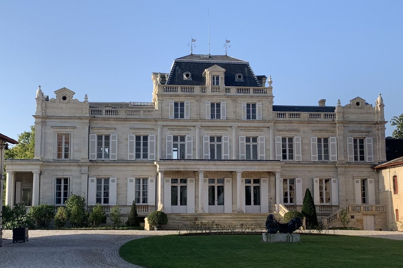 Château neoclássico com gramado circular sob céu azul