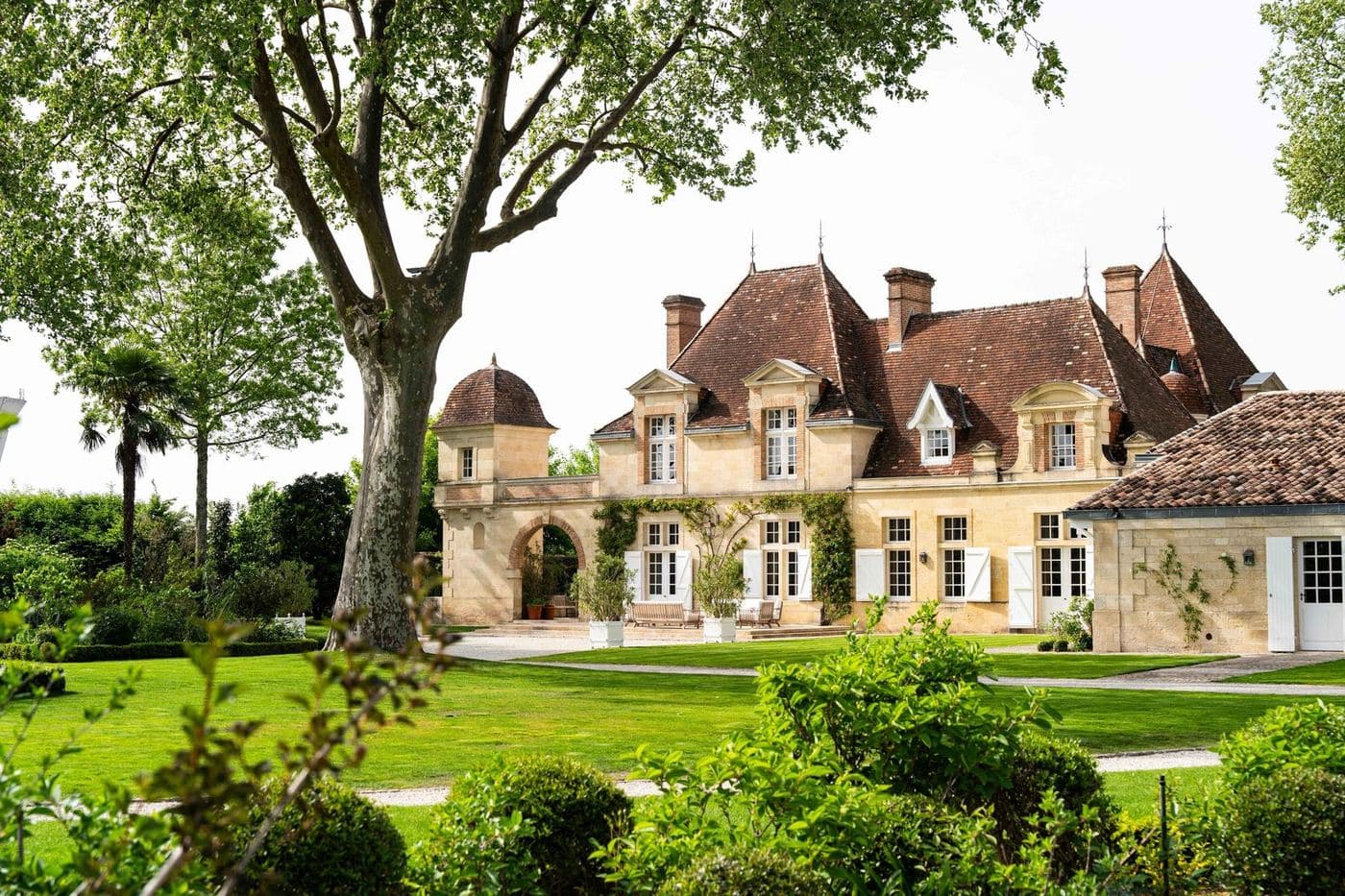 Château de pedra com telhados de telhas cercado de árvores e gramado