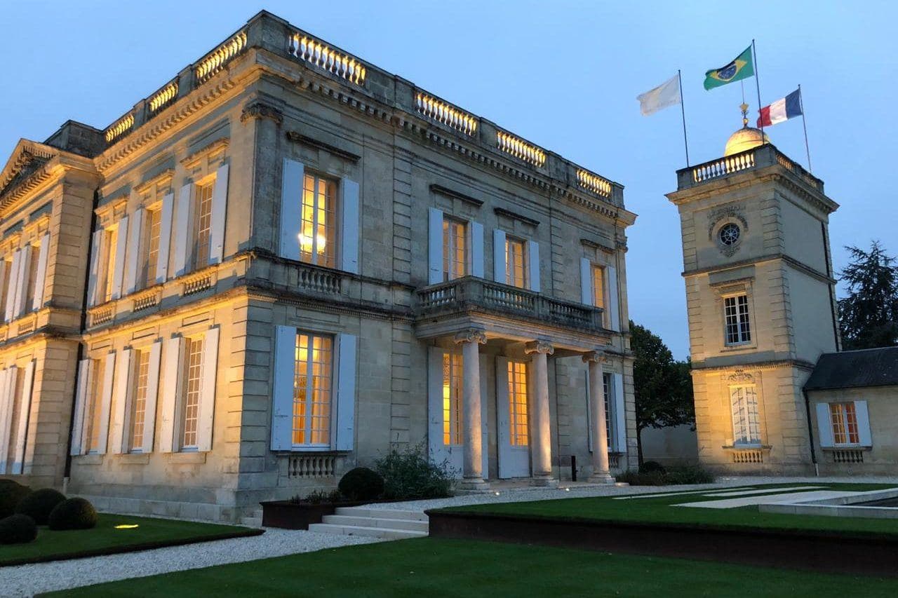 Château Gruaud Larose iluminado ao entardecer, com torre e bandeiras