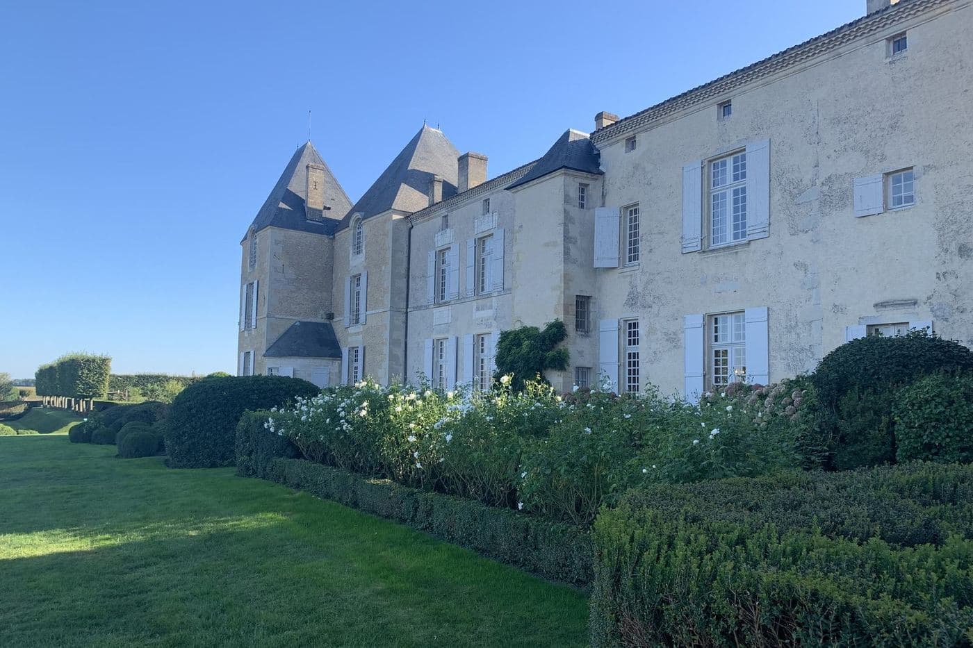 Château d'Yquem com jardim e fachada de pedra sob céu azul